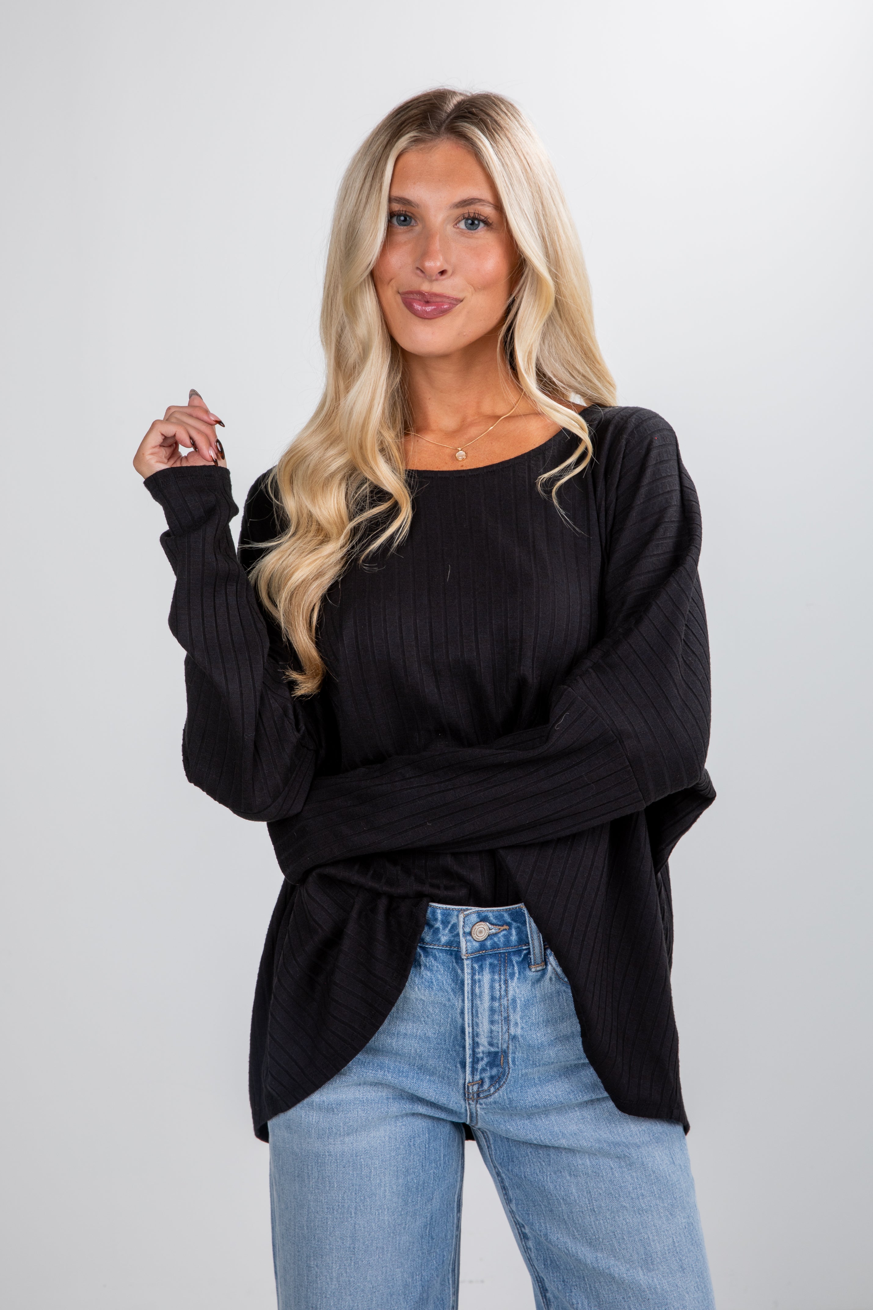 Woman wearing a black sweater and blue jeans against a white background