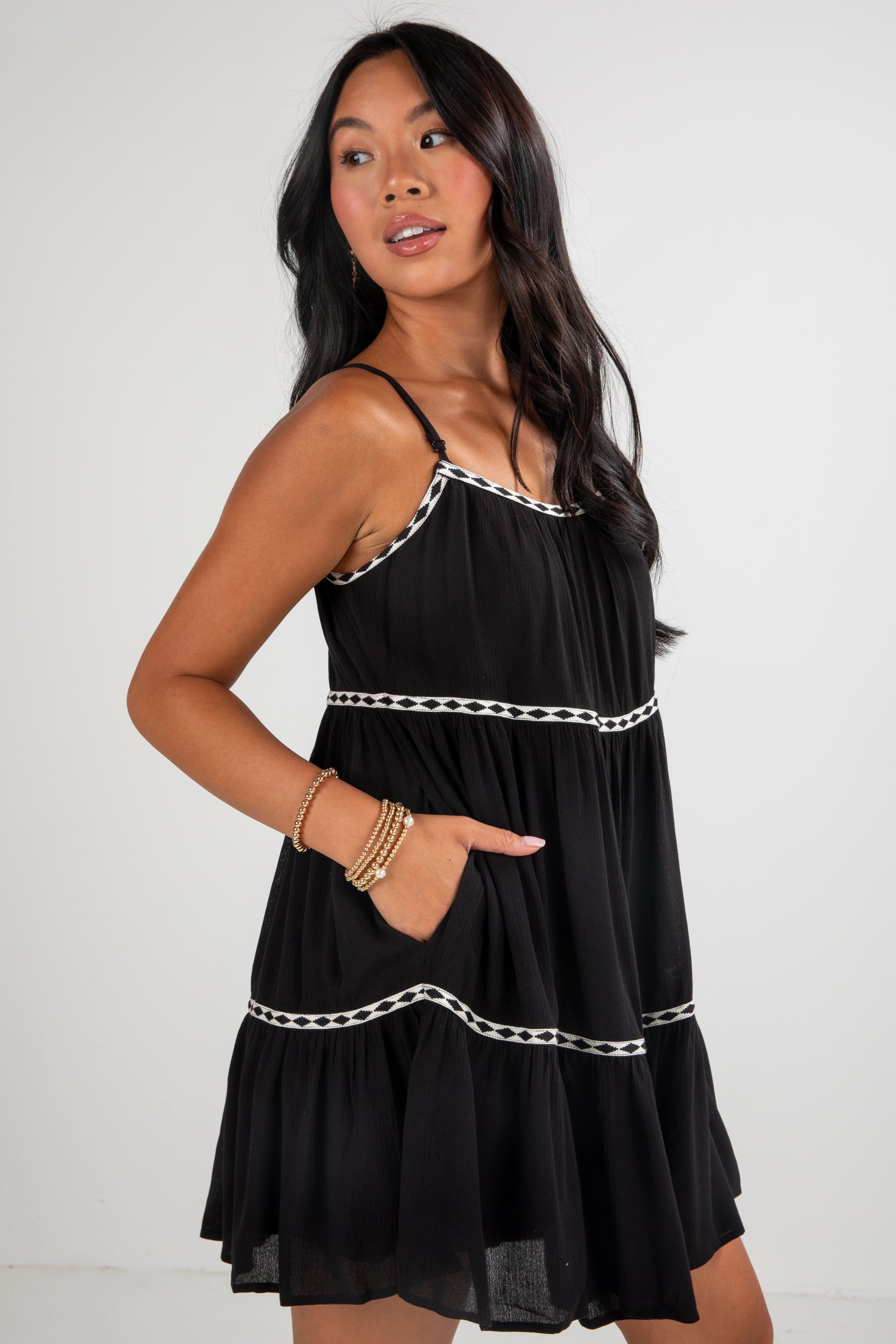 Woman wearing a black dress with white trim against a plain background