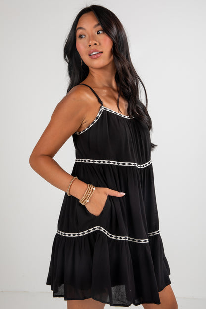 Woman wearing a black dress with white trim against a plain background