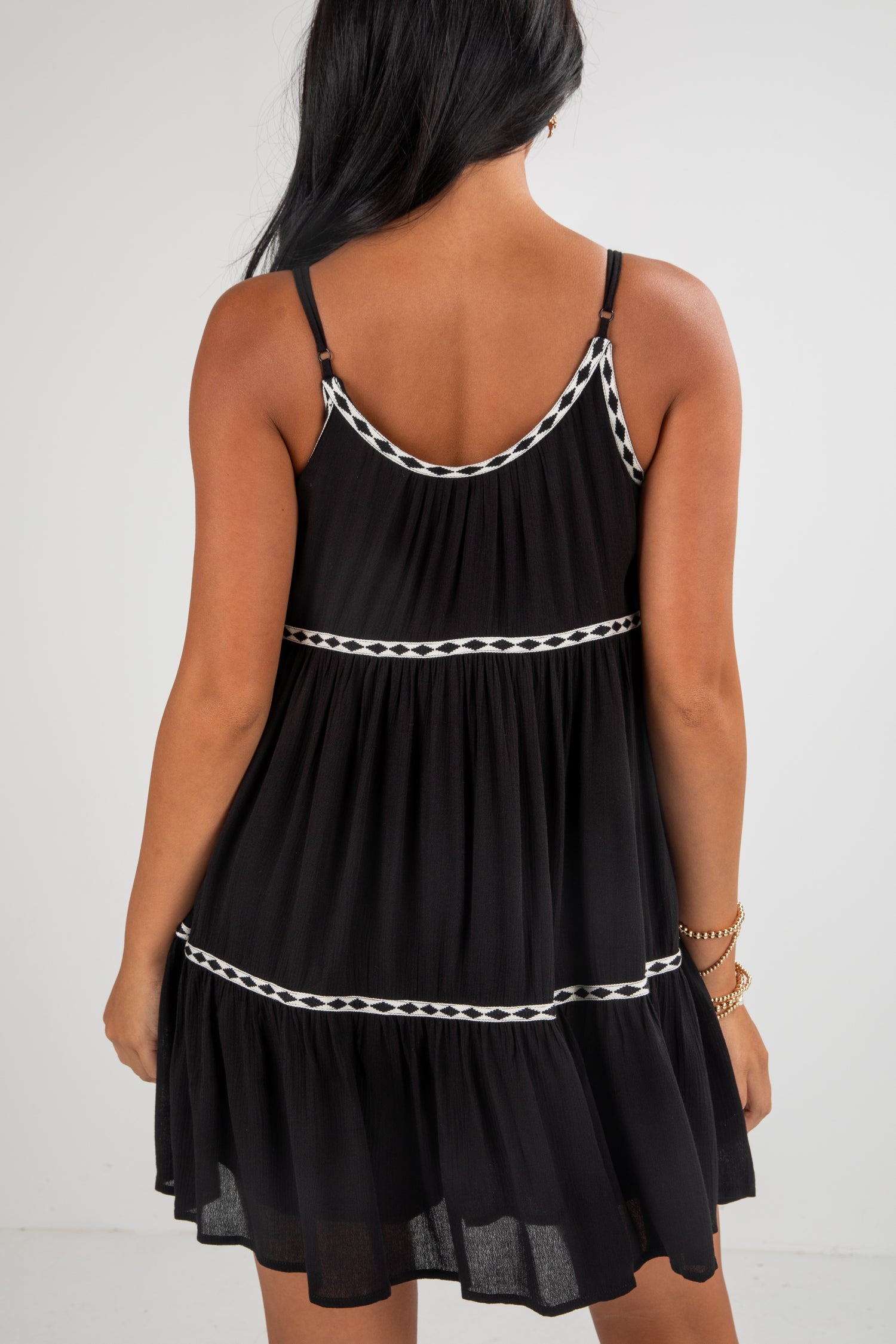 Black dress with white trim on a plain background