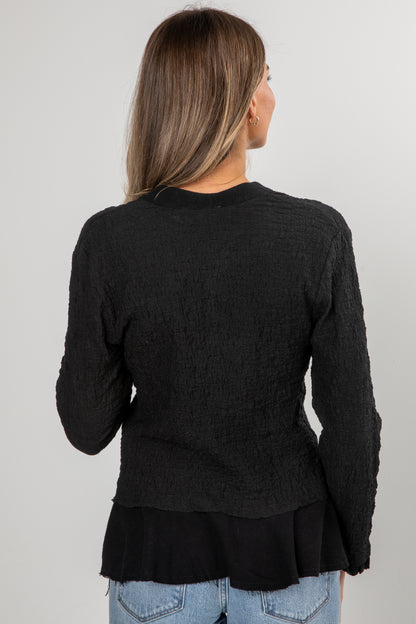 Black layered sweater worn by a person on a plain background