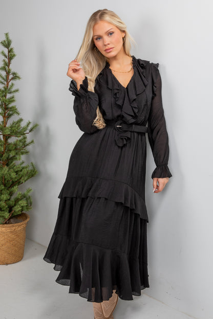 Woman wearing a black dress standing next to a potted plant on a white background