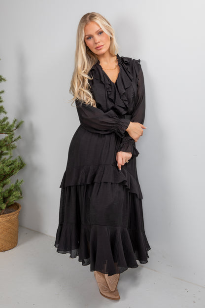 Woman wearing a black dress with ruffled layers against a white background