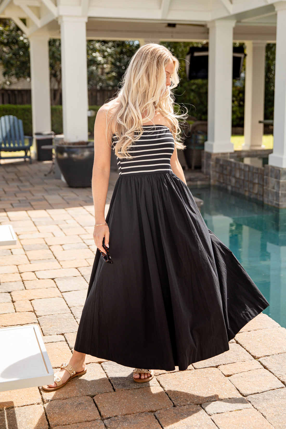 Woman in a black and white striped dress standing by a pool