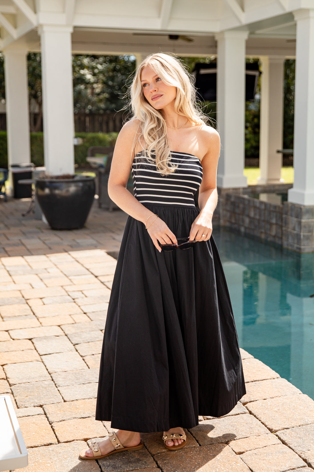 Woman in a black and white striped dress standing by a pool