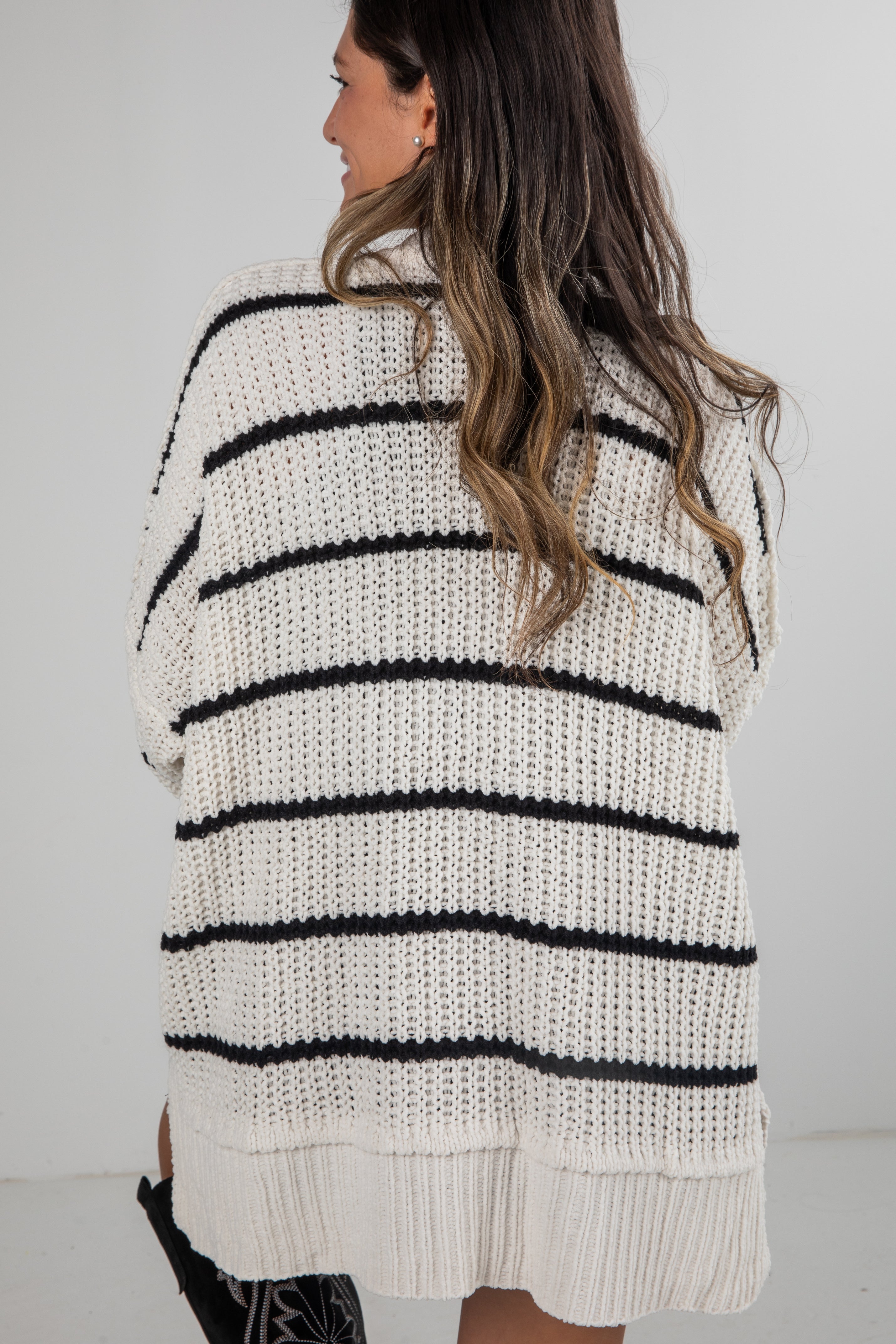 Woman wearing a white and black striped sweater against a plain background