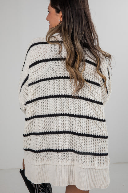 Woman wearing a white and black striped sweater against a plain background