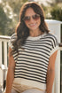 Woman wearing a black and white striped top and beige pants on a sunny day.