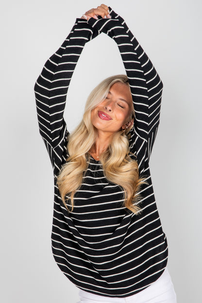 Woman wearing a black and white striped long-sleeve top against a plain background