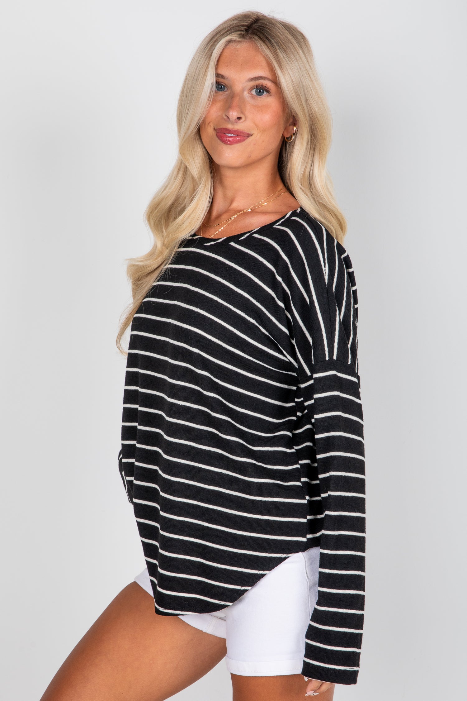 Woman wearing a black and white striped long-sleeve top on a plain background
