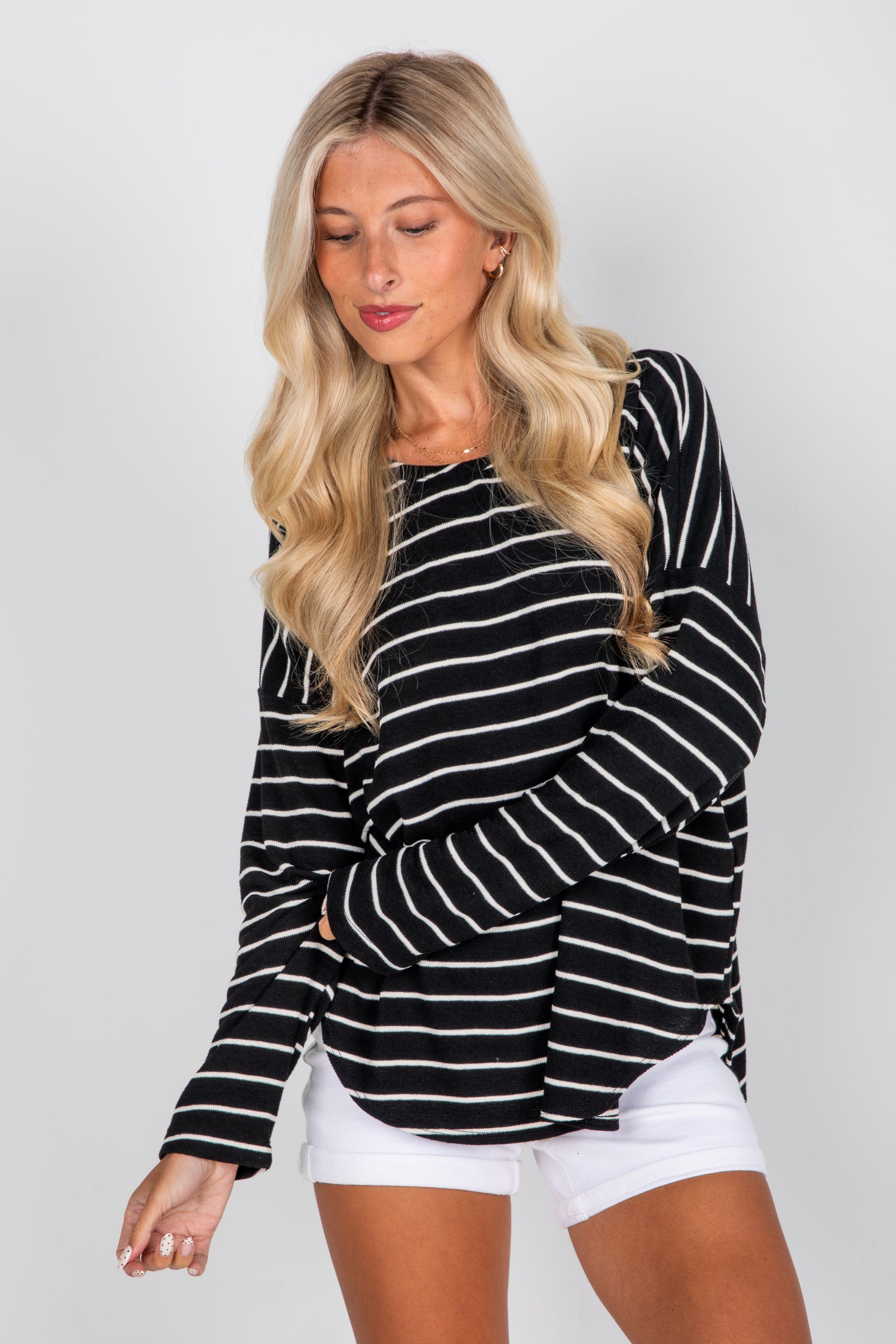 Woman wearing a black and white striped long-sleeve top against a plain background