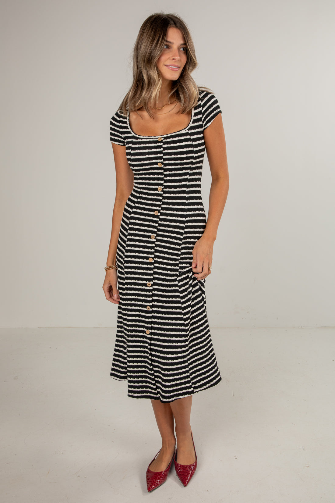 Woman wearing a black and white striped dress on a plain background