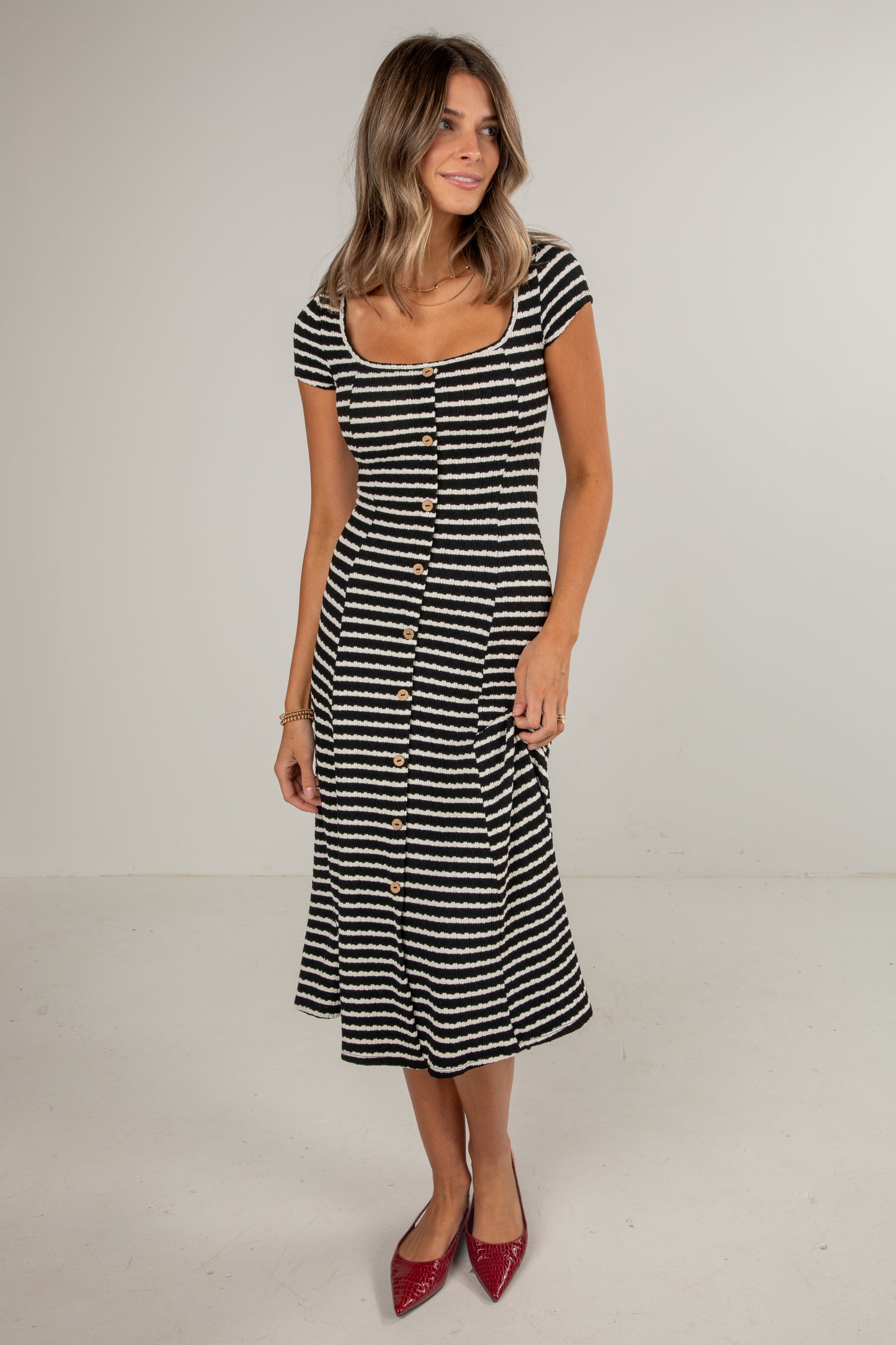 Woman wearing a black and white striped dress on a plain background