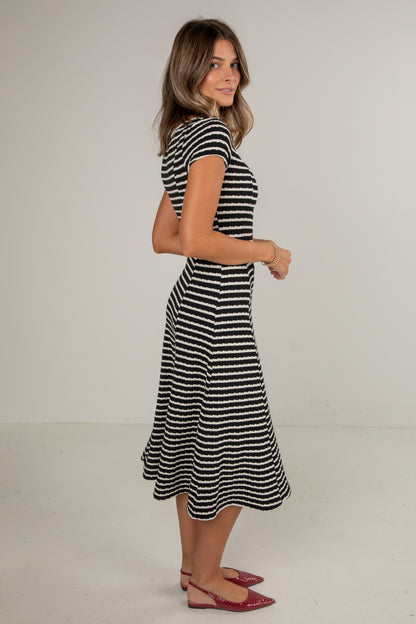 Woman wearing a black and white striped dress on a plain background