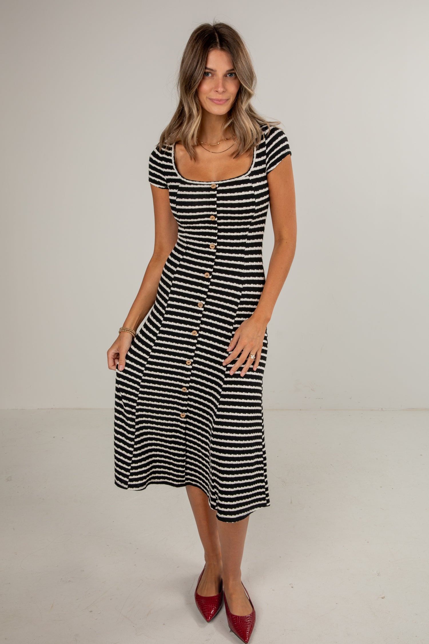 Woman wearing a black and white striped dress on a plain background