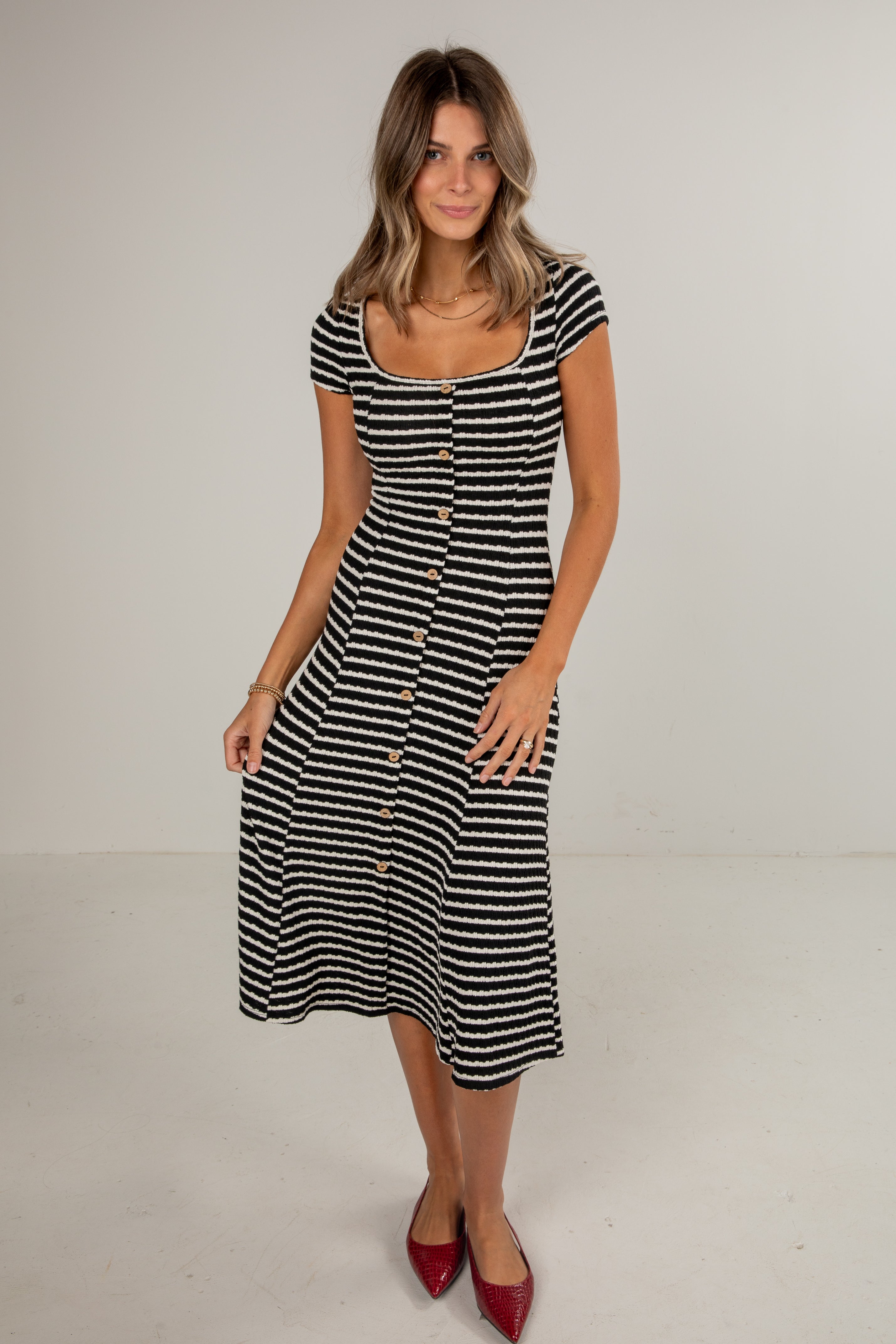 Woman wearing a black and white striped dress on a plain background