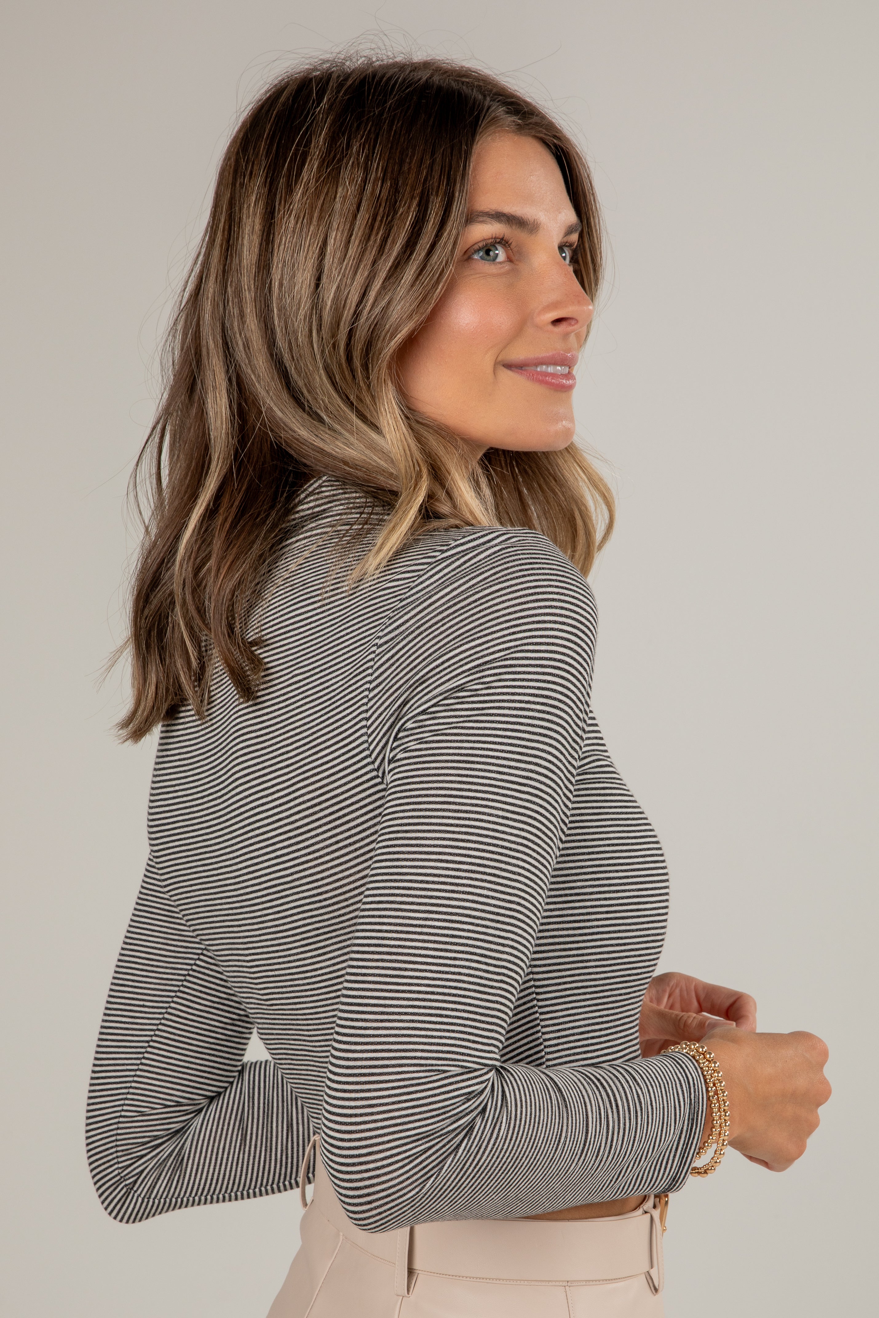 Woman wearing a striped long-sleeve top against a plain background