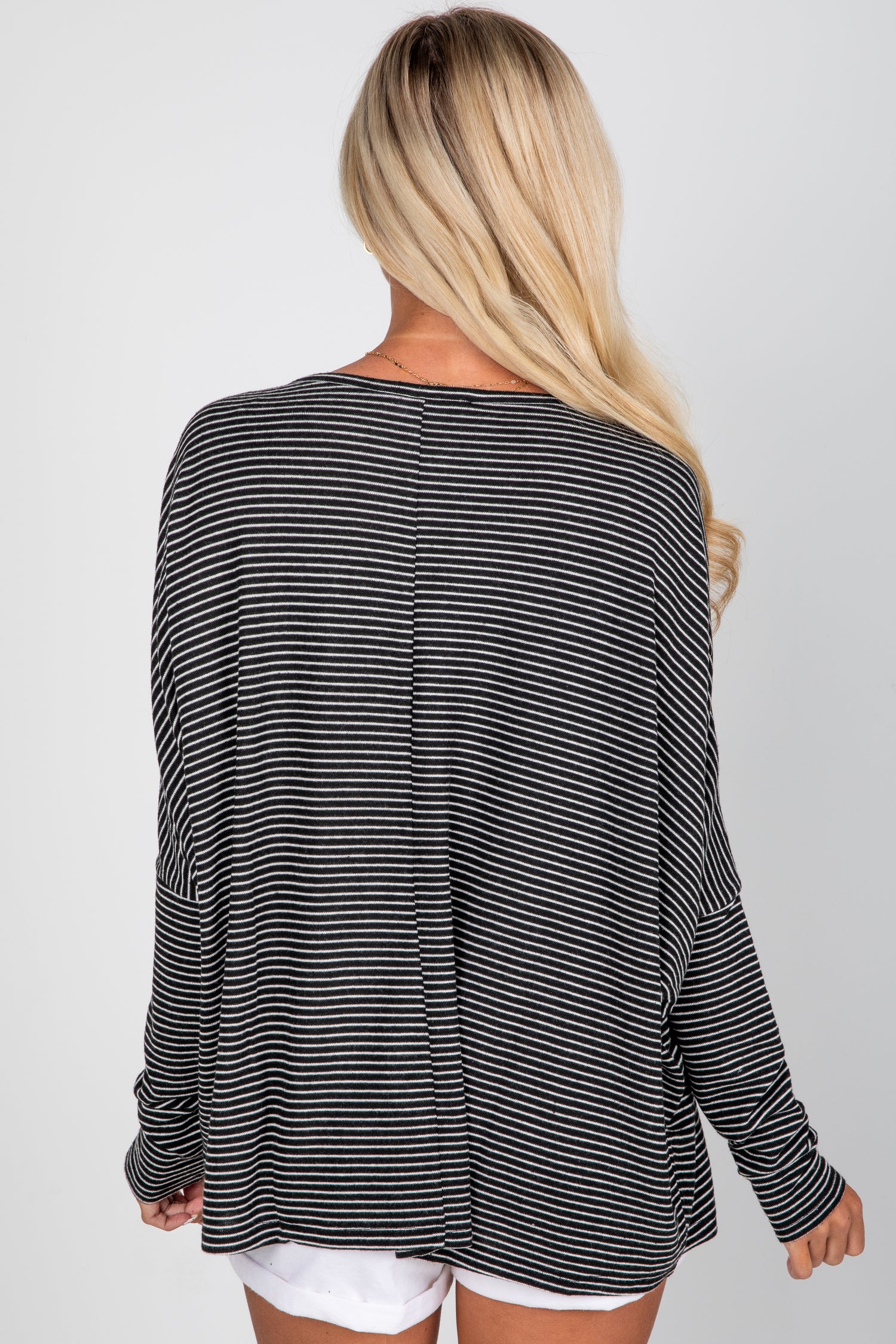 Person wearing a black and white striped long-sleeve top on a plain background