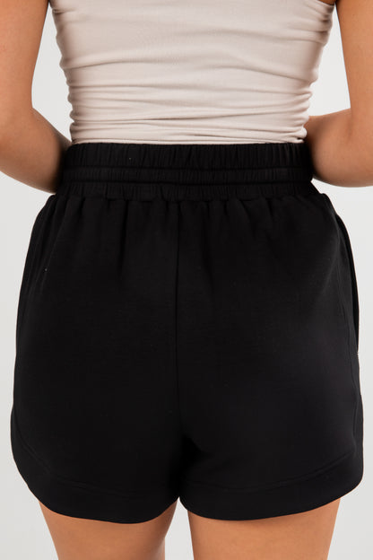 Black shorts worn by a person on a plain background