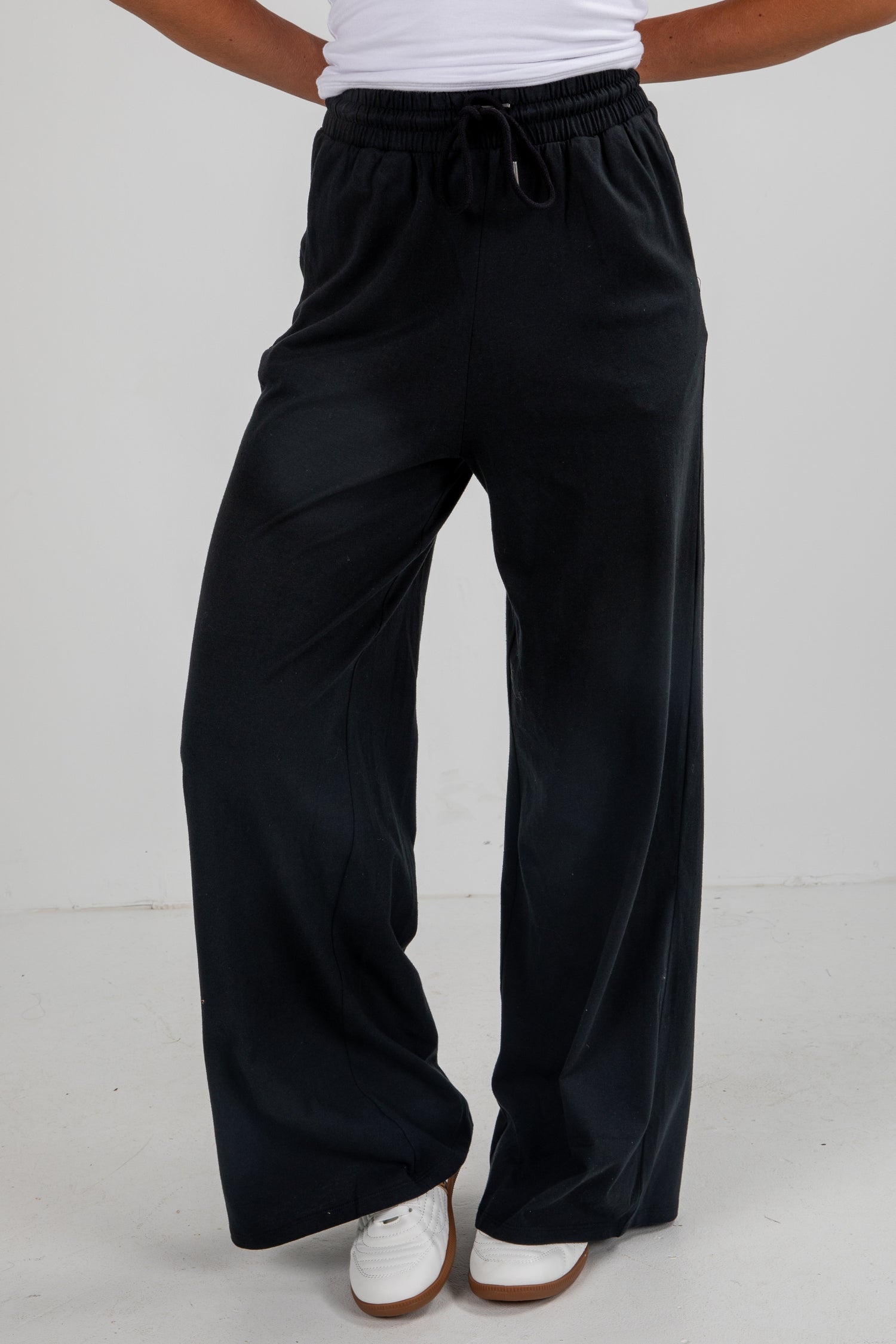 Black wide-leg pants worn by a person on a white background