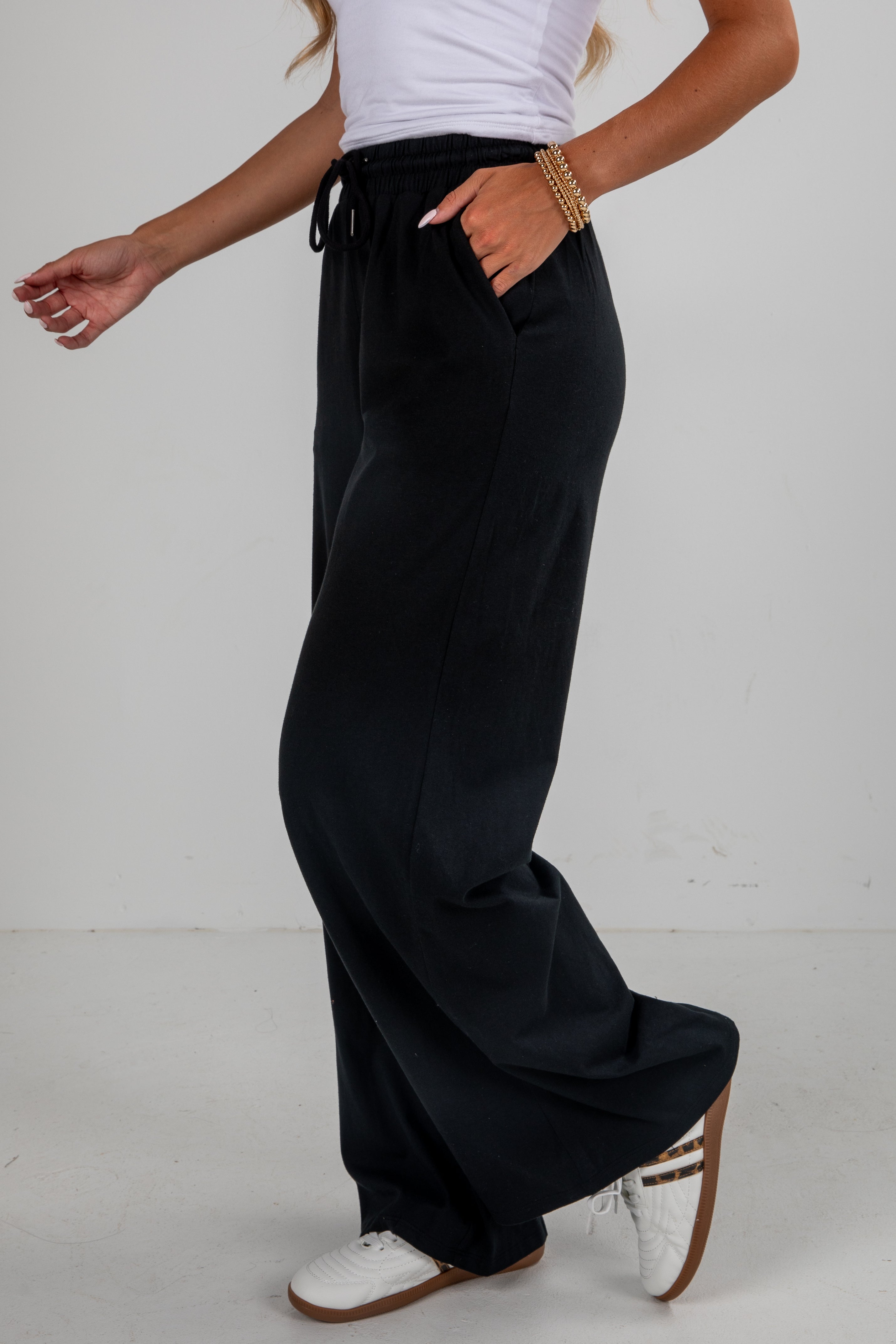 Person wearing black wide-leg pants with a white background
