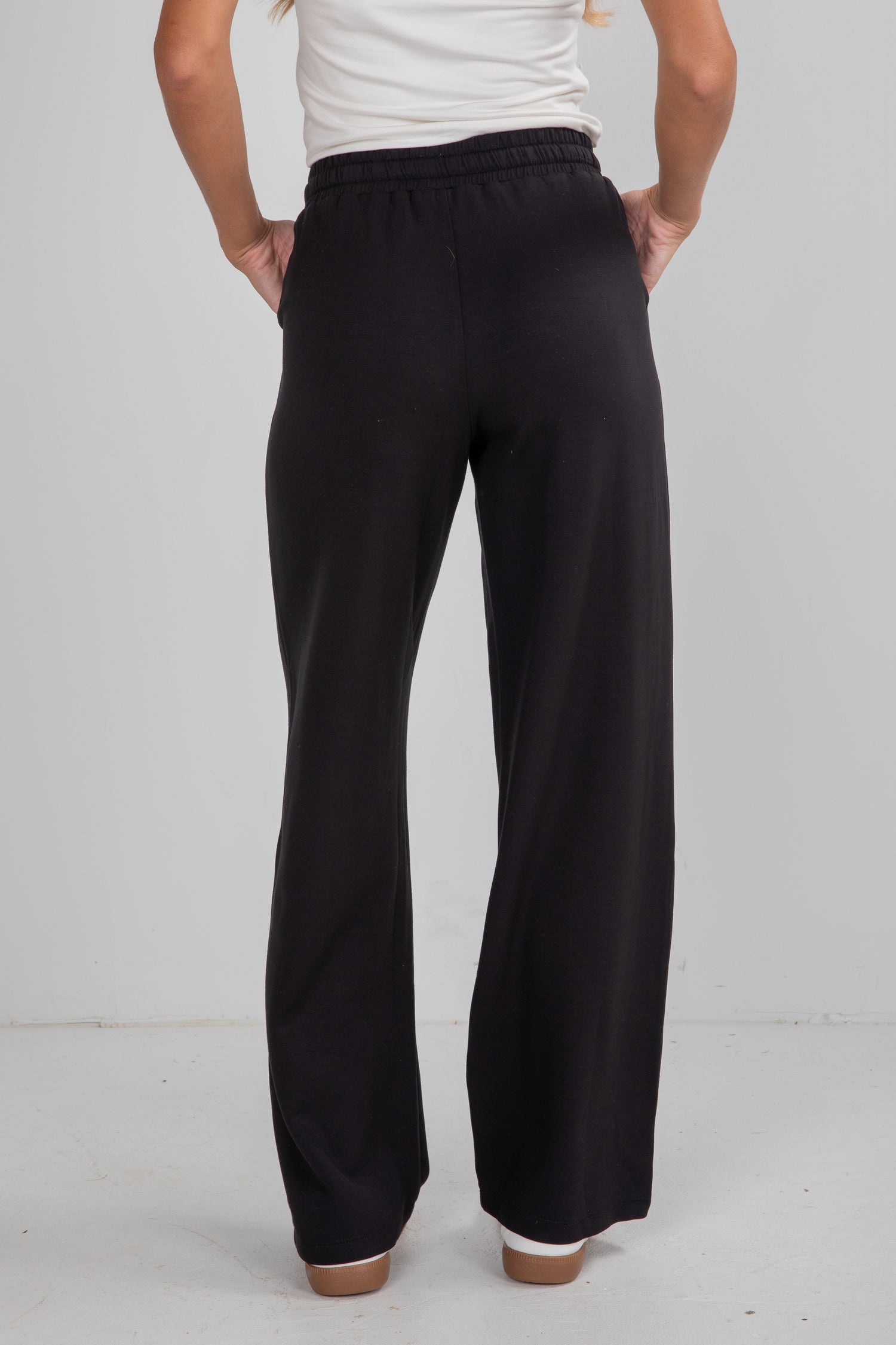 Person wearing black pants on a plain background