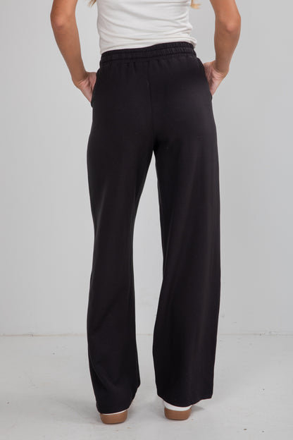 Person wearing black pants on a plain background