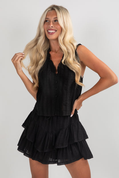 Woman wearing a black tiered dress against a plain background