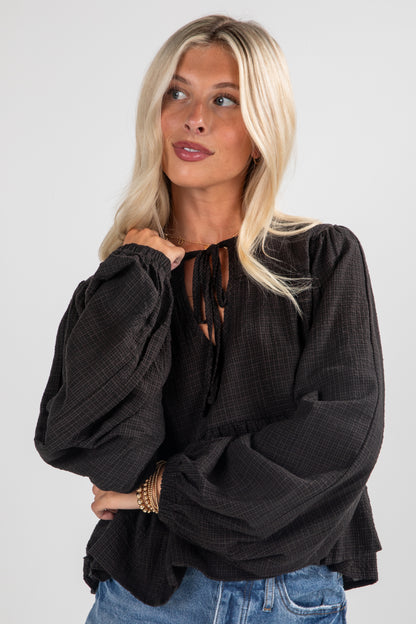 Woman wearing a black oversized blouse with a plain background