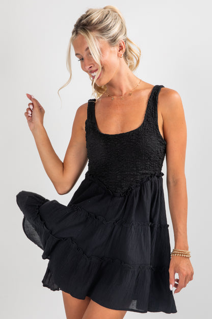 Woman wearing a black sleeveless dress on a plain background