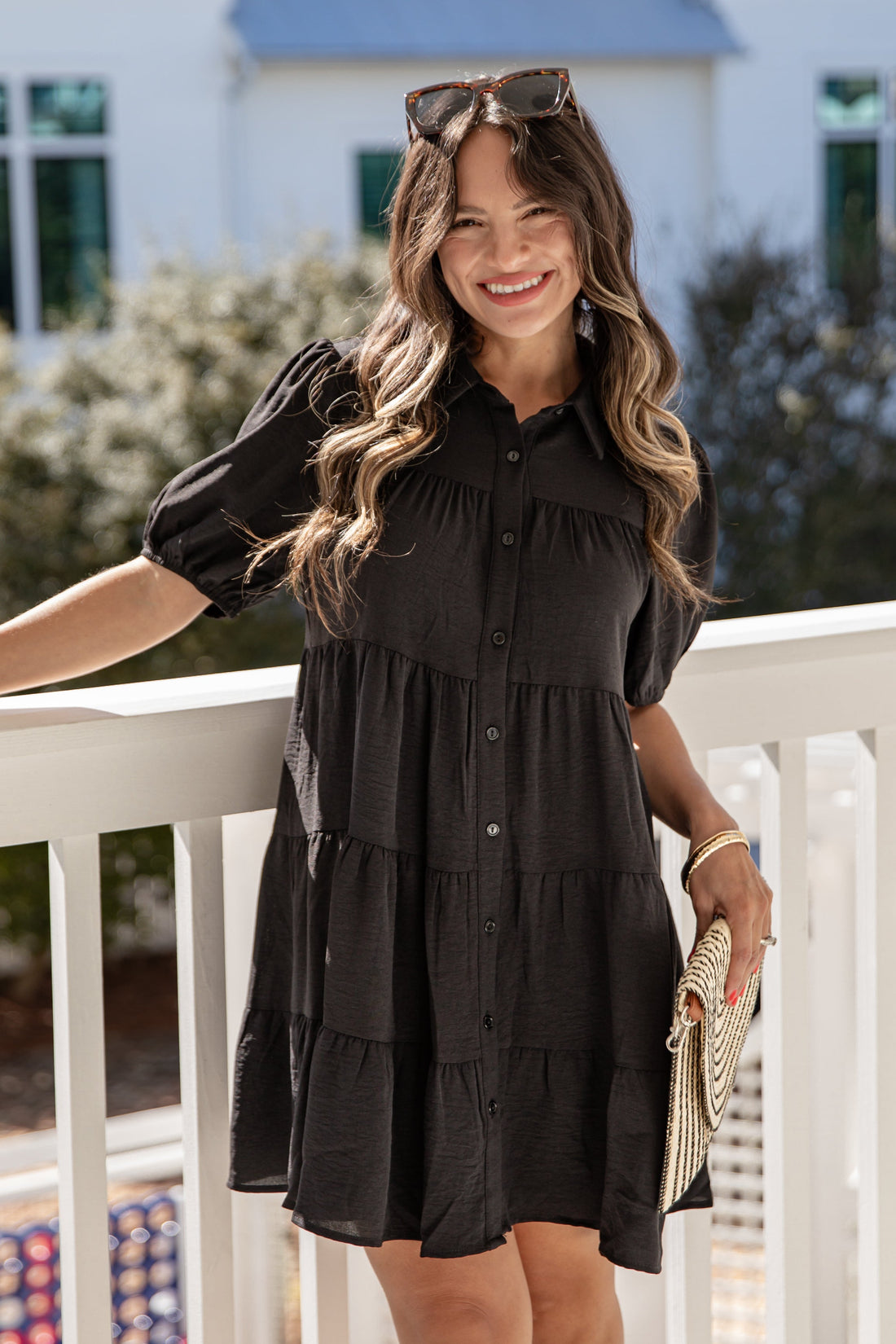 Woman in a black dress standing on a balcony with a blurred background