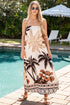Woman in a tropical dress standing by a pool with palm trees in the background