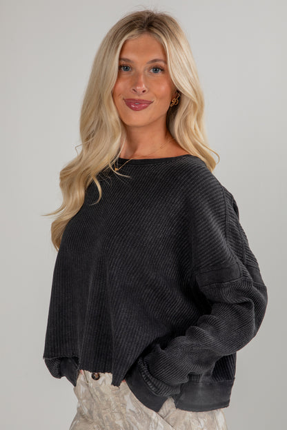 Woman wearing a dark gray sweater against a plain background