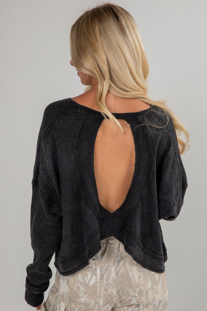 Black open-back sweater worn by a person on a plain background