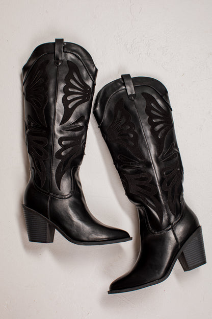 A pair of black leather knee-high cowboy boots with decorative cutout stitching, displayed on a light textured background.