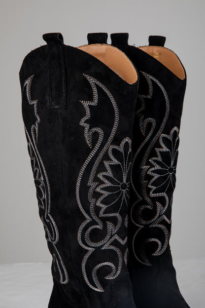 Black cowboy boots with intricate silver embroidery on a white background