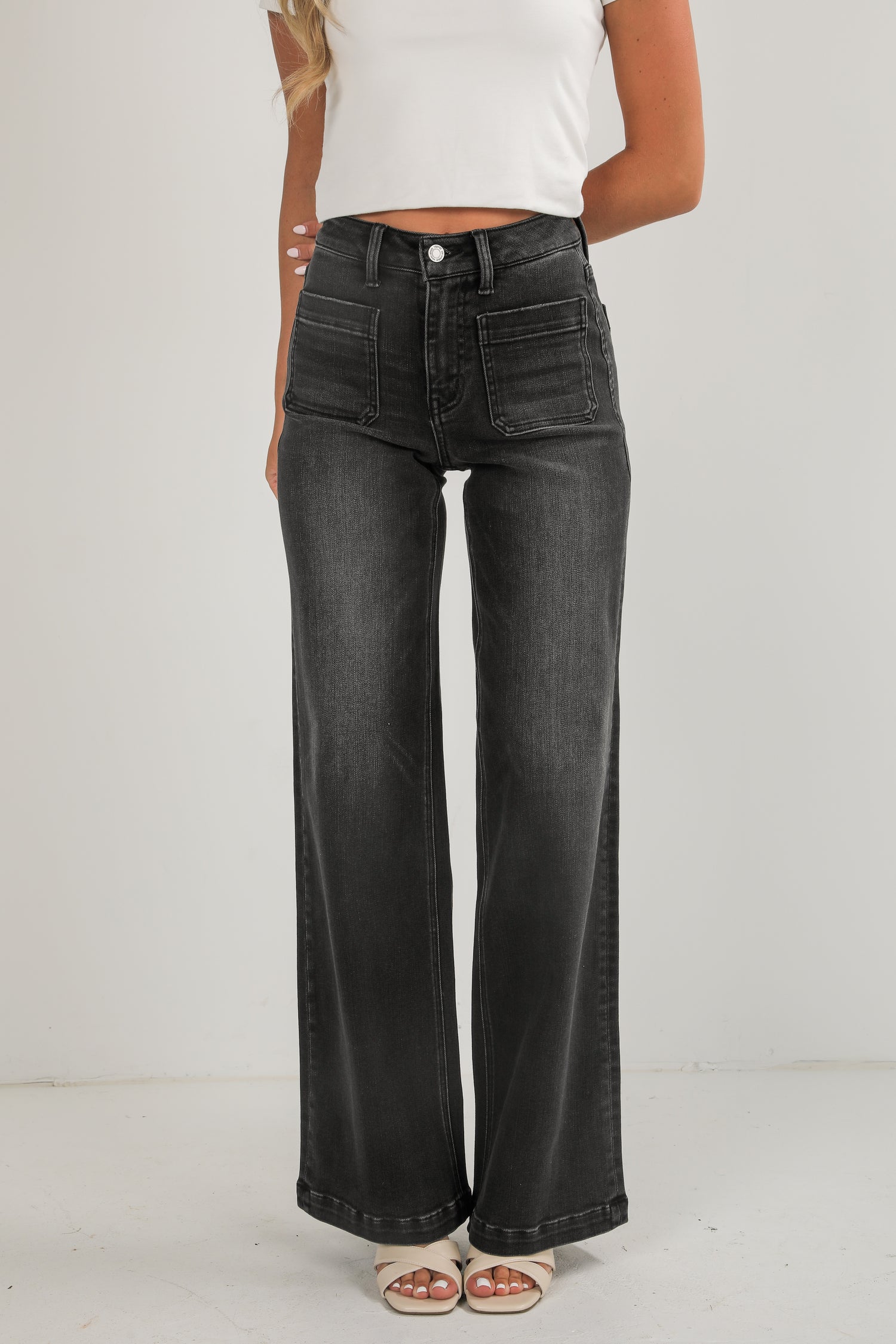 Person wearing black wide-leg jeans on a plain background