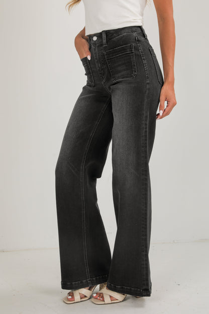 Person wearing black flared jeans on a white background