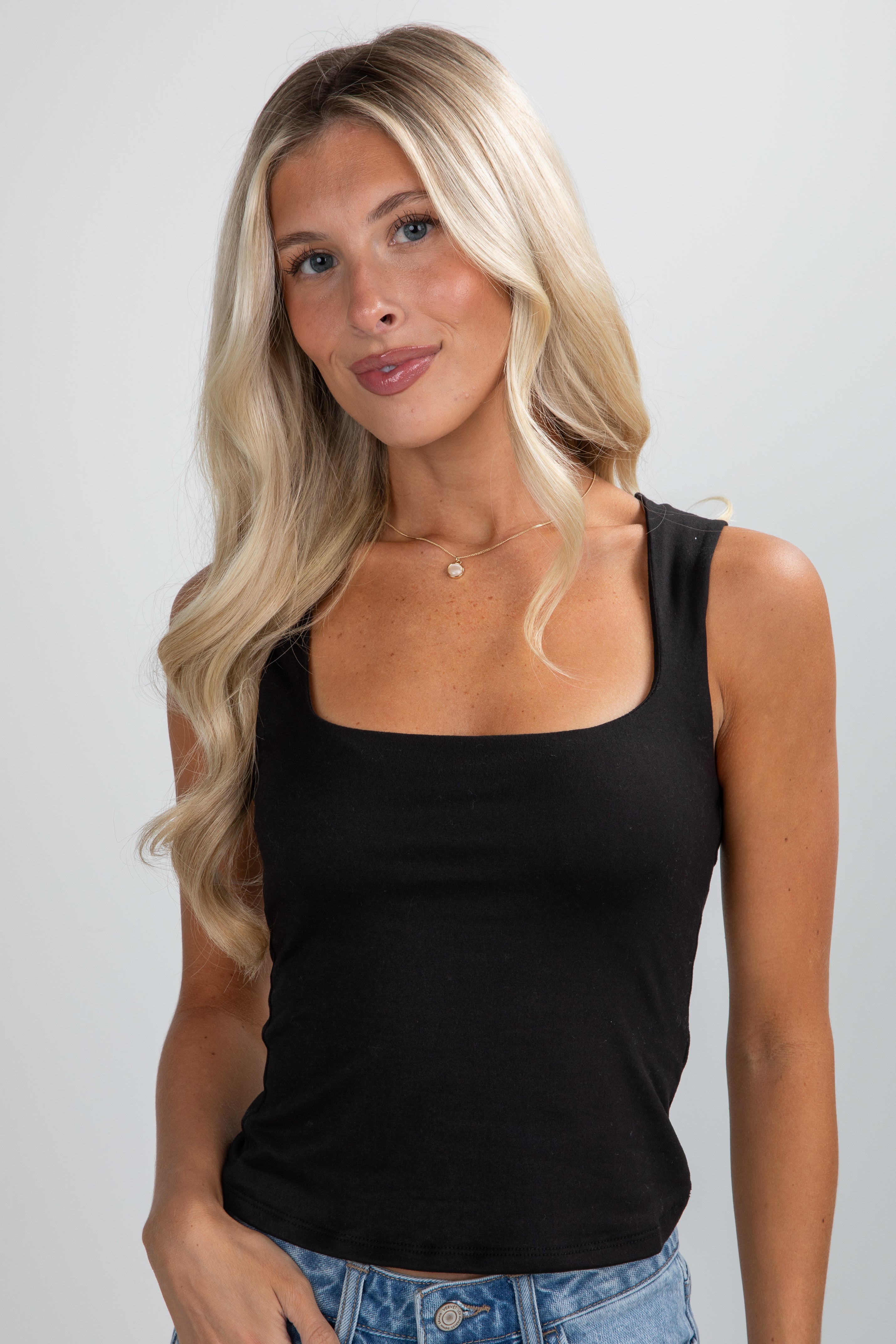 Woman wearing a black tank top against a plain background