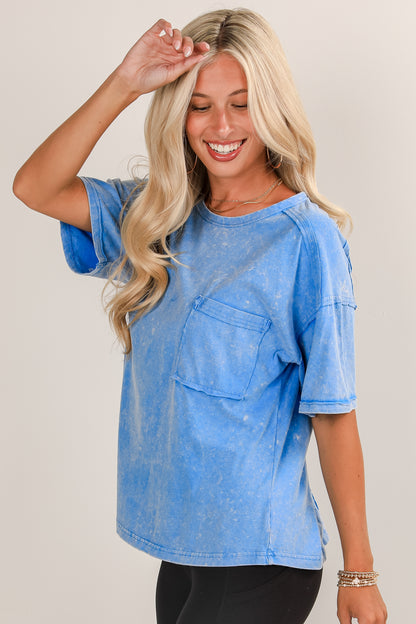 Woman wearing a blue distressed shirt with a neutral background
