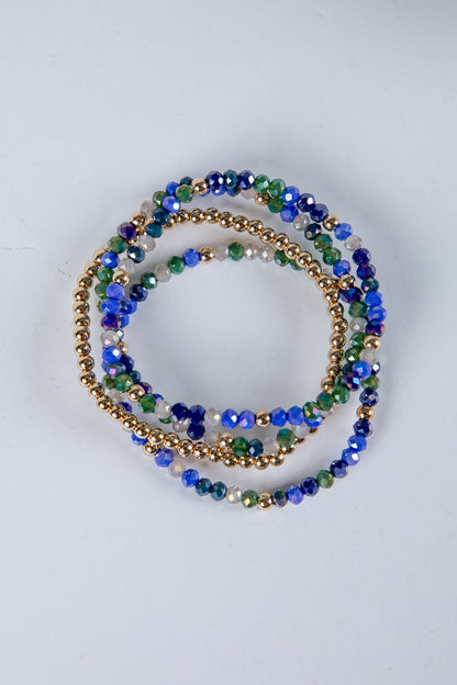 Set of beaded bracelets in blue, green, and gold on a light gray background