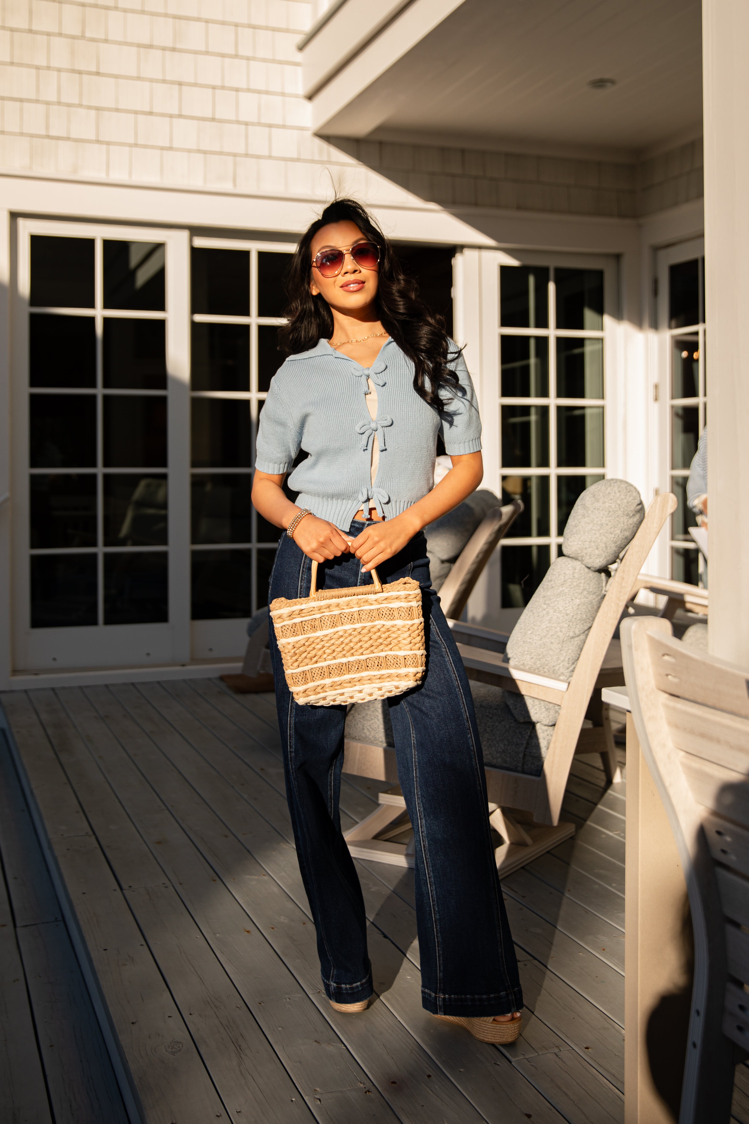Woman holding a woven bag on a wooden deck