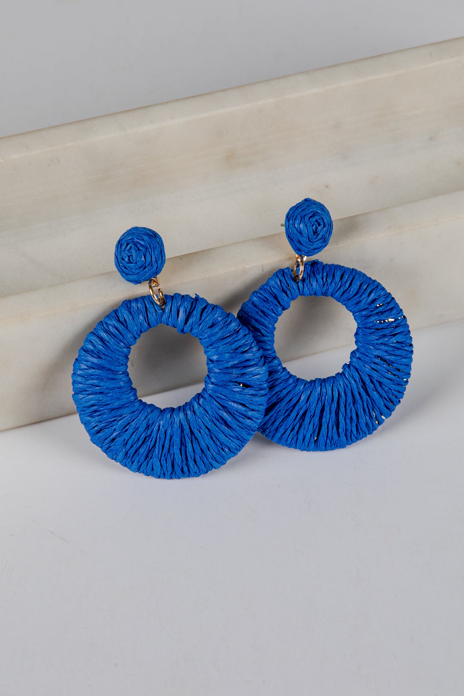 Blue hoop earrings on a light gray surface