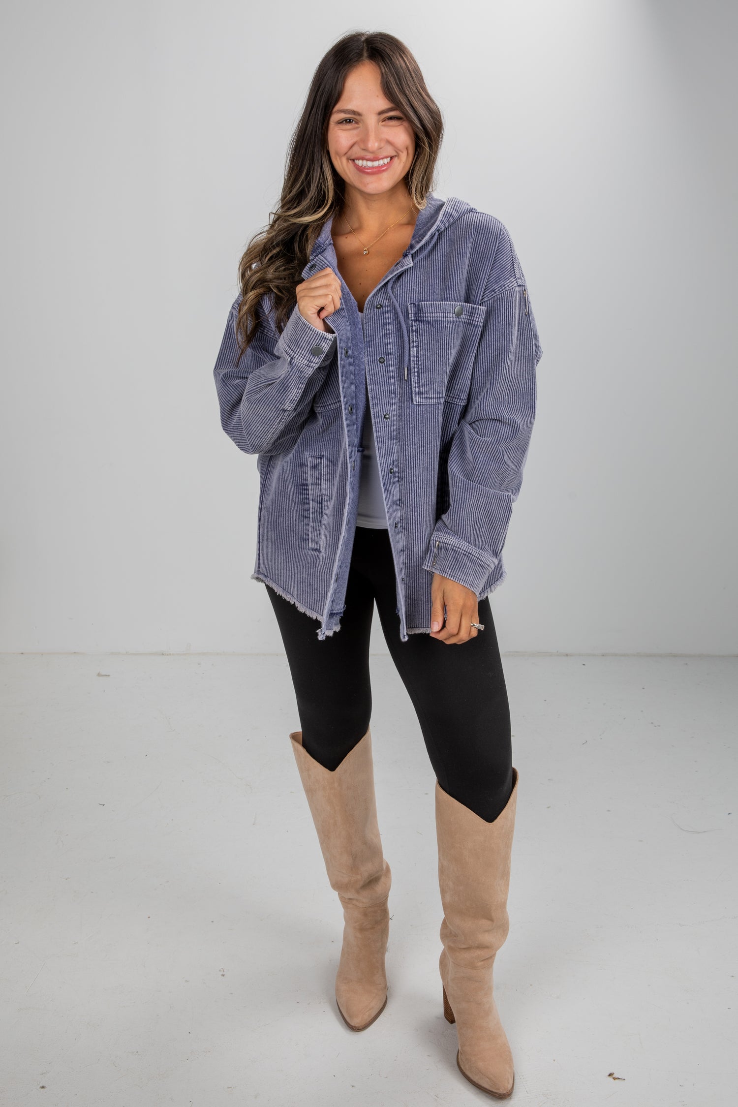 Woman wearing a denim jacket, black leggings, and tan knee-high boots on a white background