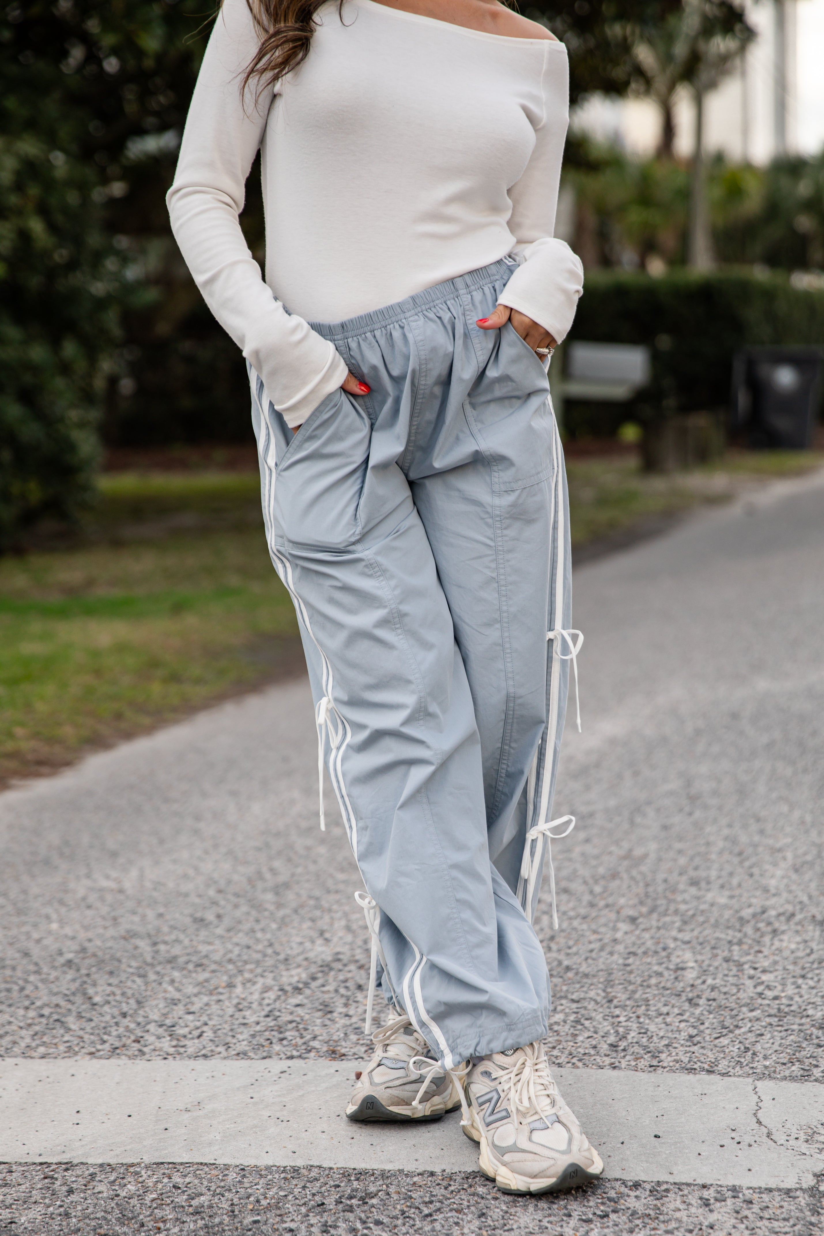 Person wearing light blue pants with white stripes and a white top on a road.