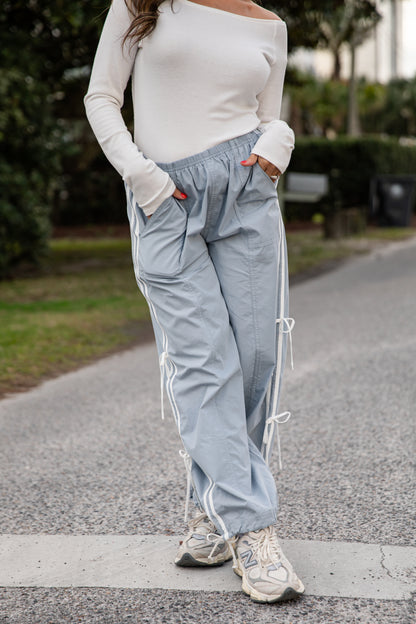 Person wearing light blue pants with white stripes and a white top on a road.