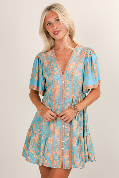 Woman wearing a blue and orange patterned dress on a plain background