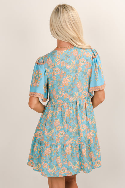 Woman wearing a blue floral dress against a plain background