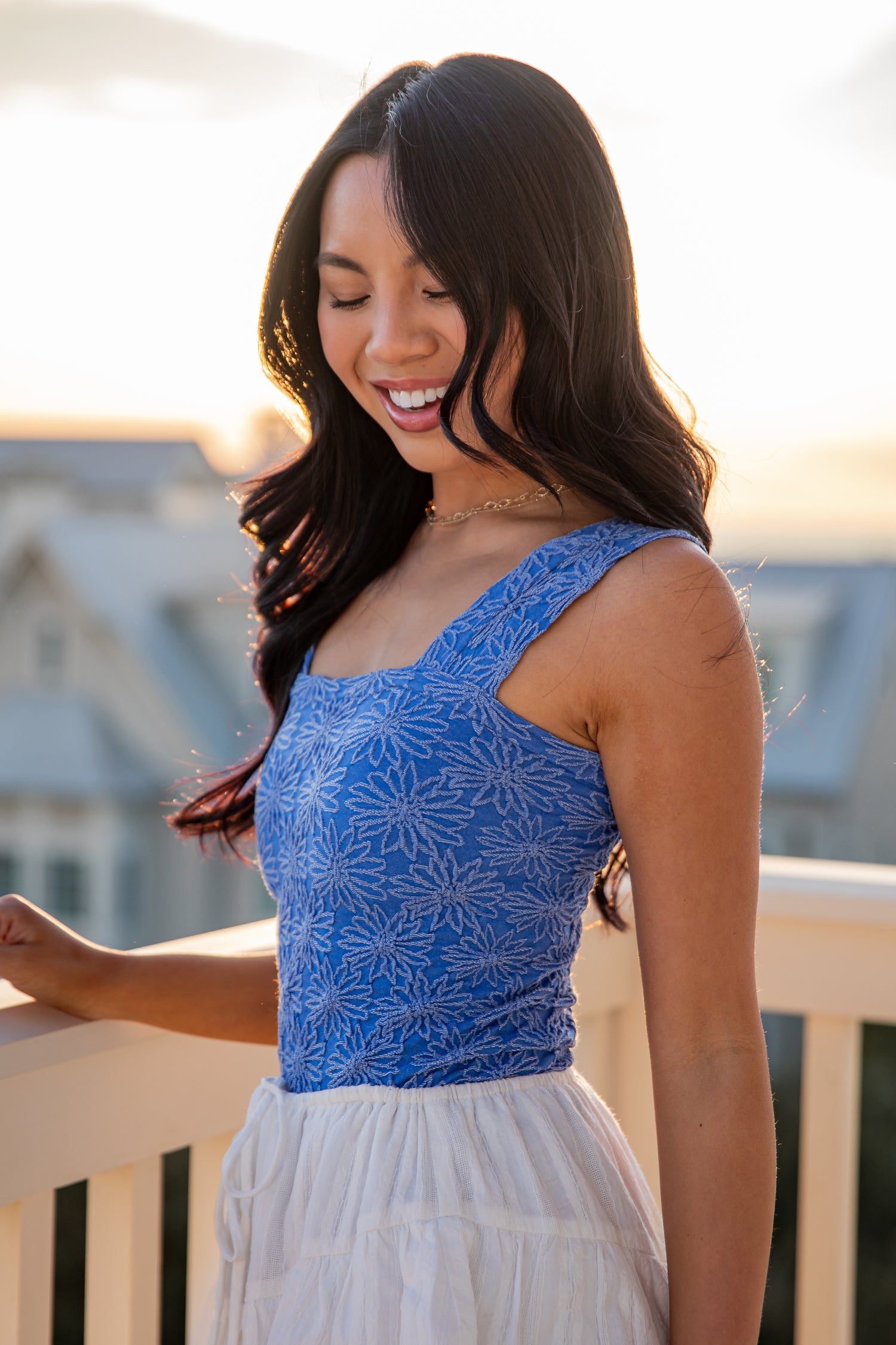 Woman wearing a blue top and white skirt standing outdoors.