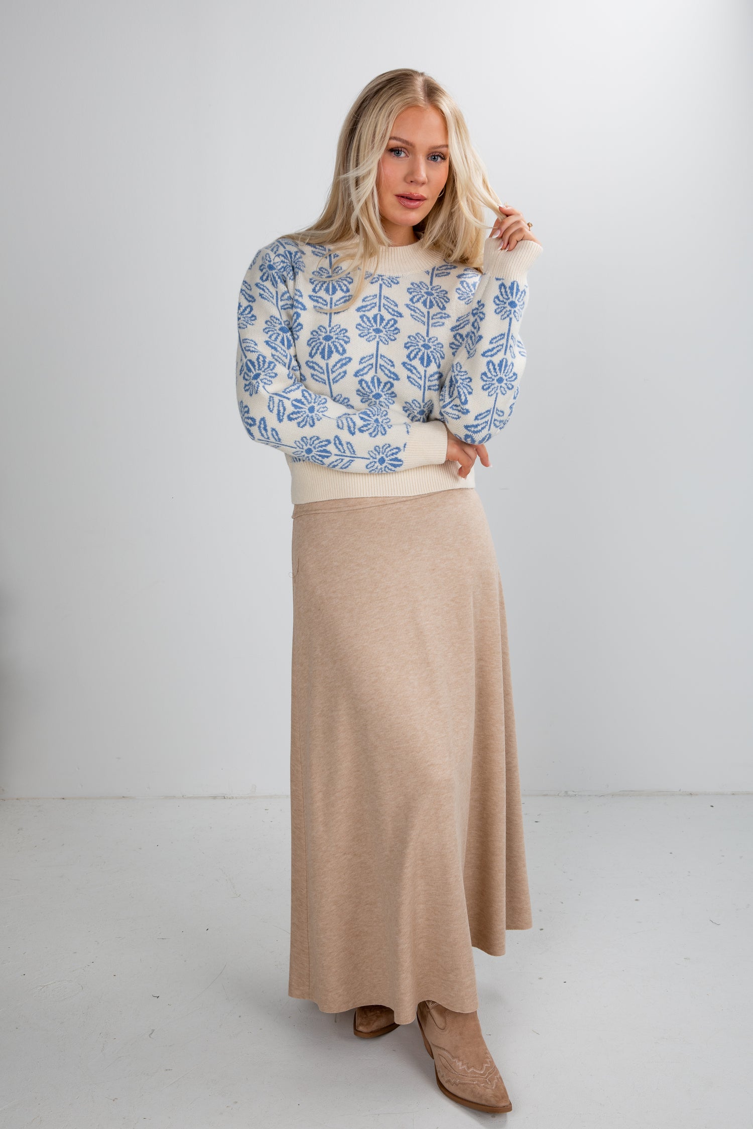 Woman wearing a floral sweater and beige skirt on a white background